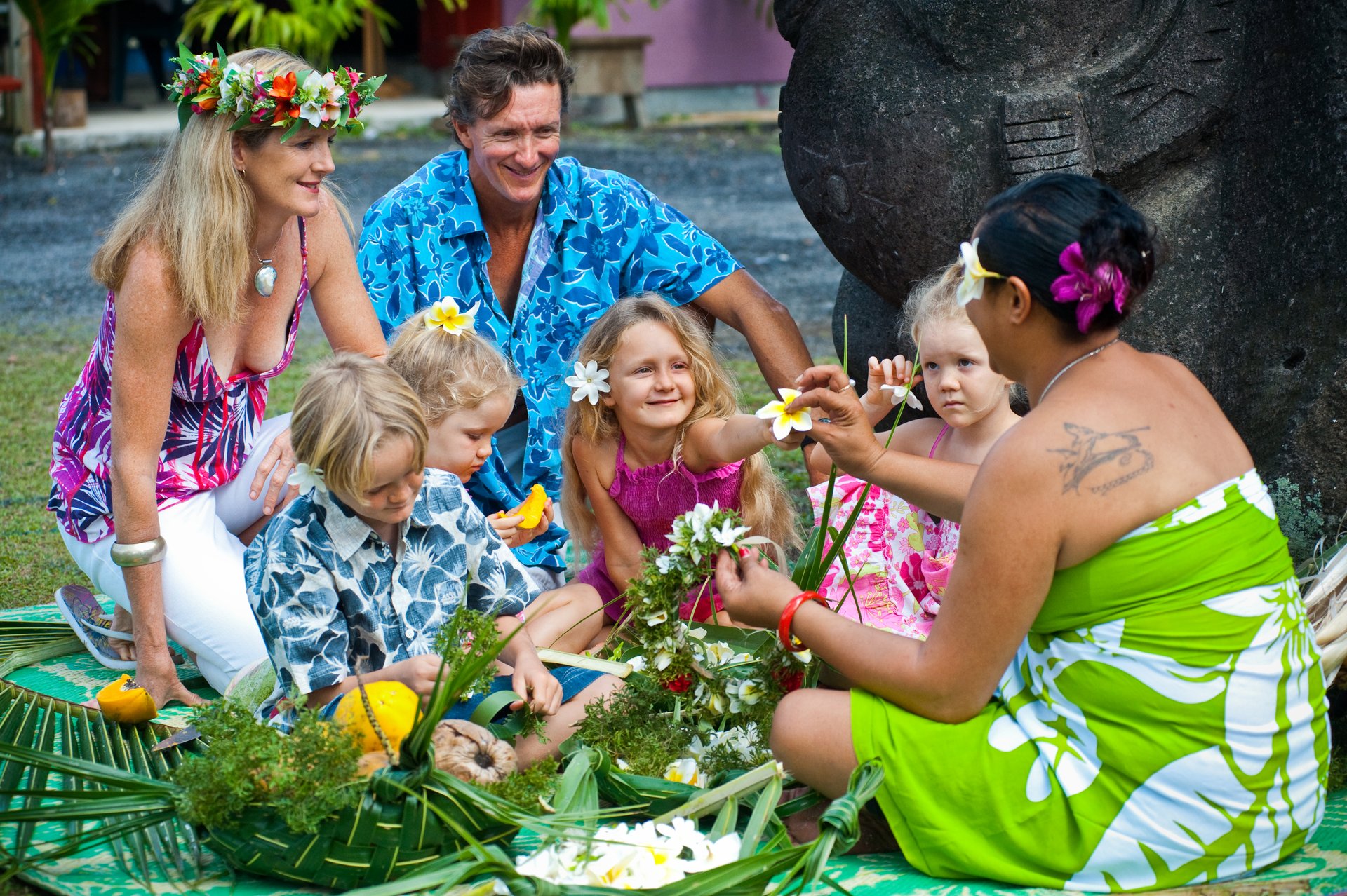Family with local person making flower necklaces Enjoying cultural experiences