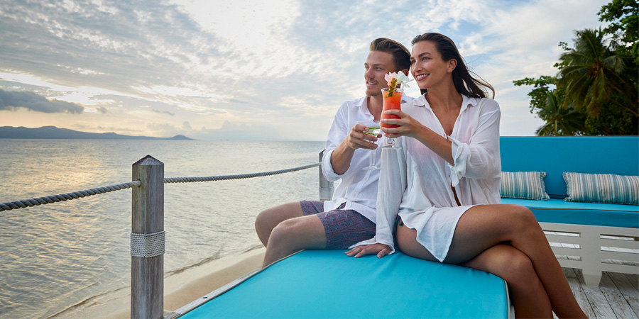 Reconnect and reinvigorate with romantic interludes in Fiji A couple cheers to time together at sunset, overlooking the water