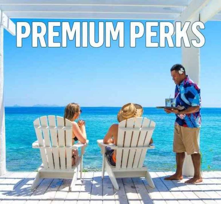 Couple enjoys endless ocean views from Malamala Beach Club, while their waiter serves cold beverages