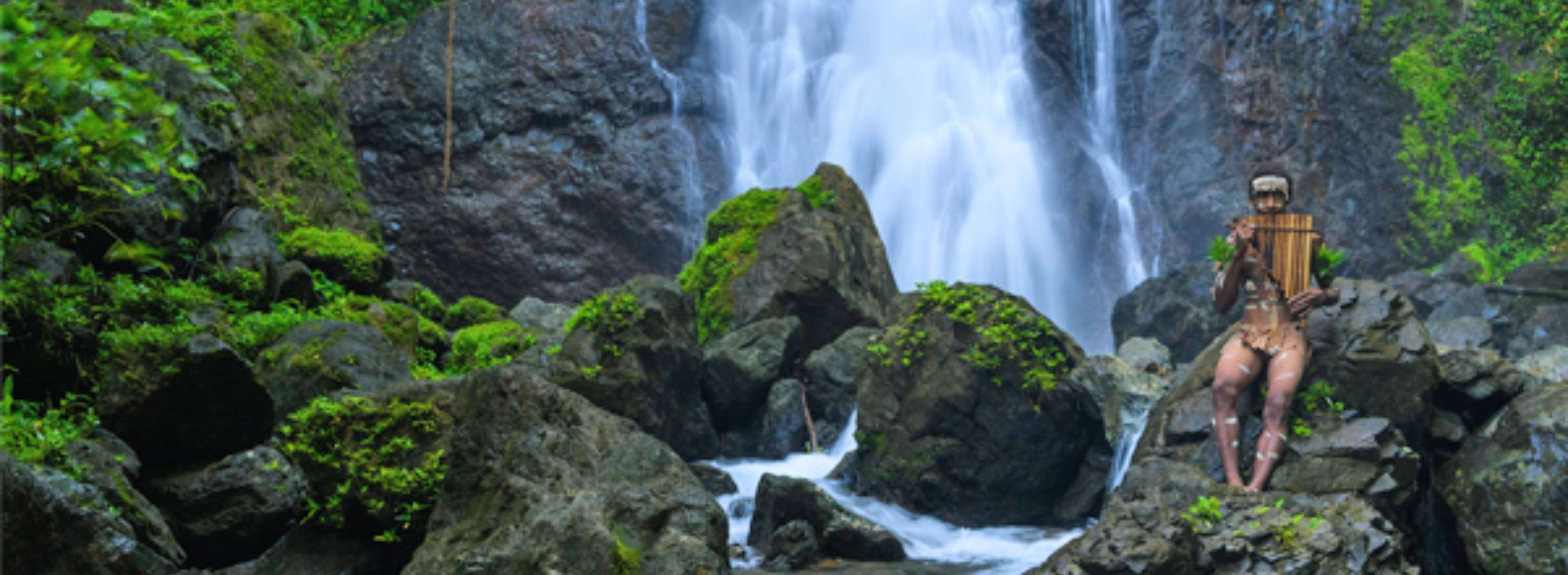 local man playing flute by waterfall