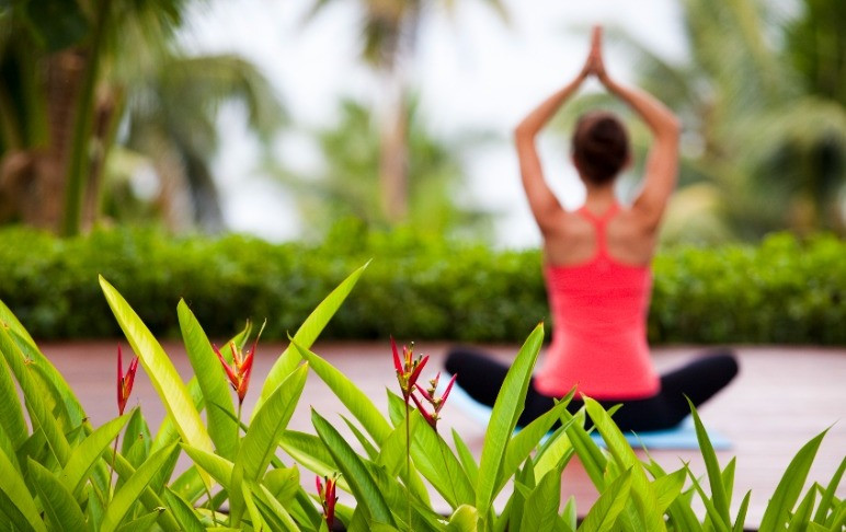 Yoga Retreat Fiji sitting woman doing yoga pose behind garden