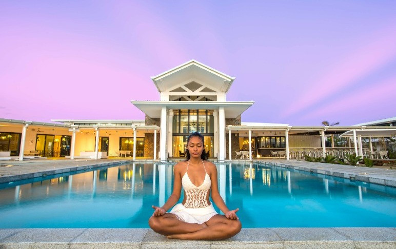 woman yoga posing in front of pool at Taumeasina resort