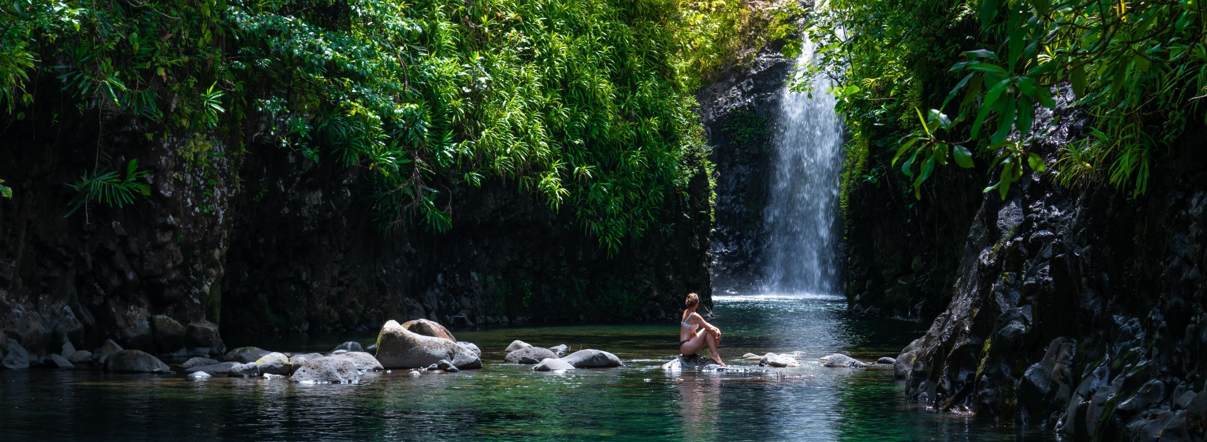 waterfall image with person sitting on a rock